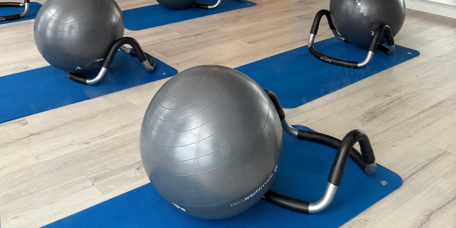 Mujer realizando ejercicios en una máquina cadillac V2 con ayuda de una monitora en una sala de Esencia Pilates. Clases de pilates en Villa del Prado Valladolid